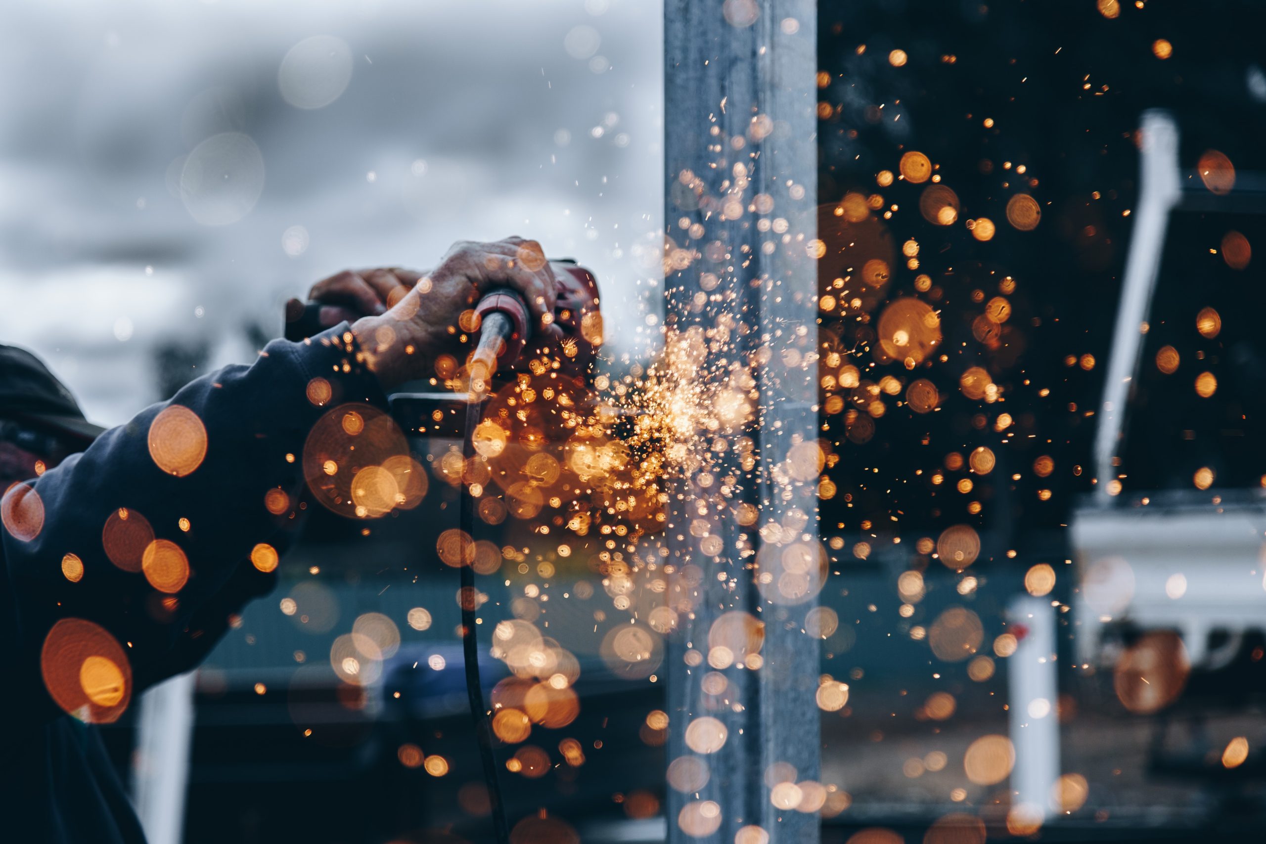 Man using tool on wood, sparks flying. Photo by Christopher Burns